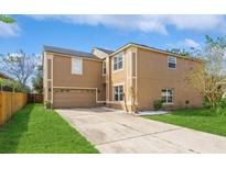 Tan two-story house with a two-car garage and landscaped lawn at 1344 Holly Glen Run, Apopka, FL 32703