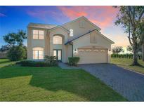 Two-story house with a large yard, double doors, and a paved driveway at 8438 Diamond Cove Cir, Orlando, FL 32836