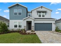Two-story home with gray and blue siding, stone accents, and a two-car garage at 1352 Silo Dr, St Cloud, FL 34771
