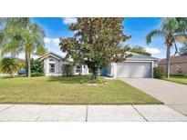 Single-story home with gray siding, attached garage, and lush lawn at 5009 Oak Tours Dr, Orlando, FL 32839