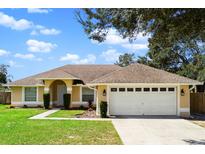 Single-story house with a two-car garage and landscaped lawn at 233 Hidden View Dr, Groveland, FL 34736