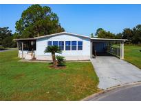 Single-wide manufactured home with carport and landscaped yard at 202 Ellsworth Ct, Kissimmee, FL 34758