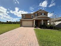 Two story home with tan exterior, paver driveway, and landscaping at 4749 Riverwalk Dr, St Cloud, FL 34771