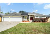 House exterior featuring a three-car garage, red door, and solar panels at 10025 Crenshaw Cir, Clermont, FL 34711