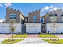 Modern two-story townhome with two-car garage and brick walkway at 1119 Boardwalk Pl, Kissimmee, FL 34747