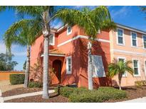 Two-story coral home with palm trees and walkway at 900 Las Fuentes Dr, Kissimmee, FL 34746