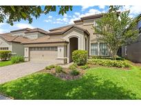 Two-story house with a three-car garage and manicured lawn at 1473 Moon Valley Dr, Davenport, FL 33896