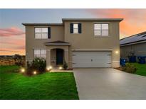 Two-story house with a two-car garage, landscaped lawn, and neutral exterior at 543 Tanaro Ln, Haines City, FL 33844