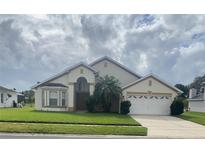Tan house with a two-car garage and landscaping at 2688 Hawthorne Ln, Kissimmee, FL 34743