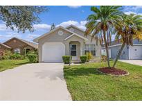 Tan house with a white garage door and palm trees at 1957 Teaberry Ct, Orlando, FL 32824