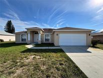 One-story house with attached garage, landscaping, and a paved driveway at 817 Highland Crest Loop, Lake Wales, FL 33853