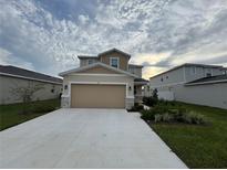 Two-story house with beige siding, two-car garage, and landscaped front yard at 853 Blue Creek Dr, Haines City, FL 33844