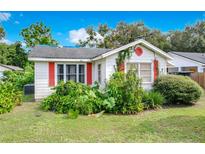 Quaint house exterior with red shutters and lush landscaping at 1907 Mae St, Orlando, FL 32806