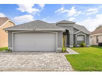 One-story home with gray siding, white garage door, and paved driveway at 12645 Crayford Ave, Orlando, FL 32837