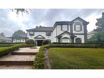 Two-story house with gray and white exterior, landscaping, and brick walkway at 8704 Crestgate Cir, Orlando, FL 32819