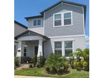 Two-story house with gray siding, stone accents, and a welcoming porch at 12500 Encore At Ovation Way, Winter Garden, FL 34787