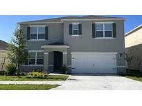 Two-story house with gray siding, white garage door, and landscaping at 1610 Newfoundland St, Lake Alfred, FL 33850