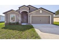 Newly constructed home with two-car garage and well-manicured lawn at 279 Fig Ct, Poinciana, FL 34759
