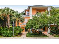 Two-story building with peach-colored facade, lush landscaping, and palm trees at 101 New Providence # 9101, Davenport, FL 33897