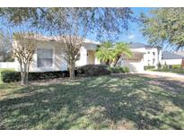 Tan one-story house with a landscaped lawn and palm trees at 3922 Old Dunn Rd, Apopka, FL 32712