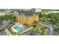 Aerial view of a hotel featuring a pool, parking lot, and surrounding landscape at 3000 Maingate Ln # 113, Kissimmee, FL 34747