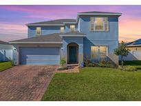 Two-story house with a gray exterior, brick driveway, and landscaped lawn at 911 Avenal, Davenport, FL 33837