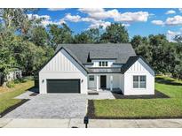 Modern farmhouse style home with a gray roof, white exterior, and a paved driveway at 155 Pearl St, Auburndale, FL 33823