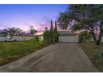 House exterior at dusk, featuring a driveway and landscaped yard at 1618 Montecito Ave, Deltona, FL 32738