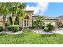 Charming single-story home with stone exterior, lush landscaping, and a two-car garage at 2108 Drive Way, Kissimmee, FL 34746