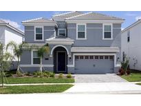 Two-story house with gray siding, three-car garage, and landscaping at 8843 Interlocking Ct, Davenport, FL 33896