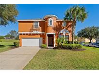 Two-story house with orange exterior, landscaping, and driveway at 2601 Isla Vista Ct, Kissimmee, FL 34747