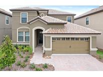 Two-story house with a large, attached garage and landscaped front yard at 1423 Thunderbird Rd, Davenport, FL 33896