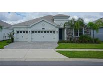 Two-story house with three-car garage and stone accents at 1490 Olympic Club Blvd, Champions Gate, FL 33896