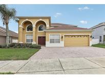 Two-story home with arched entryway and three car garage at 6526 Lake Pembroke Pl, Orlando, FL 32829
