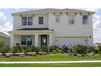 Two-story house with a front porch, two-car garage, and manicured lawn at 2626 Sage Valley Way, Winter Haven, FL 33884