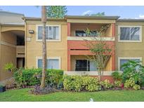 Two-story building with balcony, landscaping, and manicured lawn at 604 Kenwick Cir # 202, Casselberry, FL 32707
