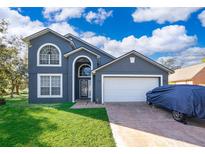 Two-story house with gray exterior, white garage door, and landscaped yard at 709 Lake Emerald Ave, Orange City, FL 32763