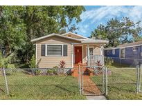 Tan house with red door, landscaping, and fenced yard at 1506 W 12Th St, Sanford, FL 32771