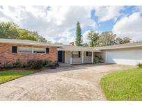 Brick ranch house with a two-car garage, landscaping, and a long driveway at 2518 Sweetwater Trl, Winter Park, FL 32789