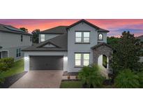 Two-story house with gray siding, brown garage door, and landscaping at 5353 White Blossom Cir, Saint Cloud, FL 34771