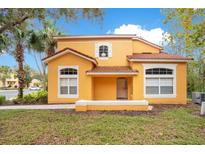 Two story yellow house with a red tile roof at 8447 Crystal Cove Loop, Kissimmee, FL 34747