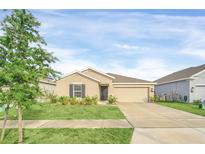 Tan house with gray shutters, two car garage, and landscaped lawn at 1119 James Paul Rd, Davenport, FL 33837