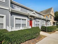 Gray townhome with red door, white picket fence, and landscaping at 4560 Spigold Court # 104, Kissimmee, FL 34746