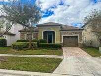 One-story house with stone and green siding, a two-car garage, and a landscaped yard at 9030 Shadow Mountain St, Davenport, FL 33896