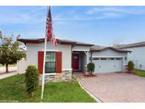 One-story home with red shutters, stone accents, and a two-car garage at 9195 Chandler Dr, Groveland, FL 34736