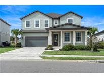Two story house with gray siding, two car garage and manicured lawn at 2094 Derwent Dr, Davenport, FL 33896