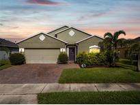 Two-story house with green exterior, brick driveway and landscaping at 3133 Queen Alexandria Dr, Kissimmee, FL 34744