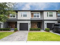 Modern two-story townhome with gray and wood siding, two-car garage, and landscaped lawn at 4410 Le Reve Ct, Kissimmee, FL 34746