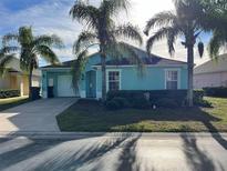 Single-story home with light teal exterior, palm trees, and a well-maintained lawn at 345 Reserve Dr, Davenport, FL 33896