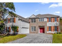 Two-story house with brick and stucco exterior, red door, and paver driveway at 3211 Eagle Watch Dr, Kissimmee, FL 34746